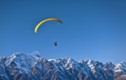 Image d'un parapente jaune au dessus des sommets enneigés